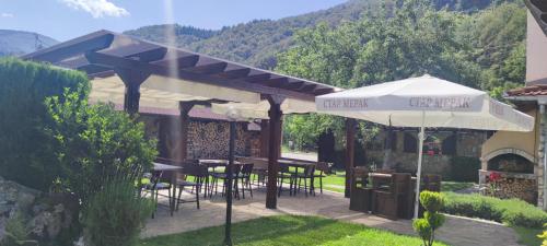 a patio with tables and chairs and an umbrella at СТАР МЕРАК in Ribarica