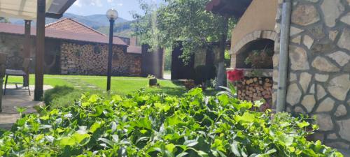 a garden in front of a building with a stone wall at СТАР МЕРАК in Ribarica