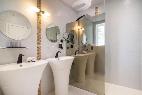 a bathroom with two sinks and two mirrors at Château de Maraval in Cénac-et-Saint-Julien