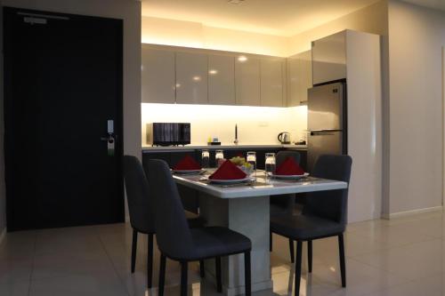 a kitchen with a table with chairs and a refrigerator at Suasana Suites Johor Bahru City Centre in Johor Bahru