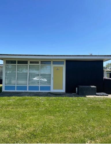 a blue building with a yellow door and a grass field at Little Spain in Selsey