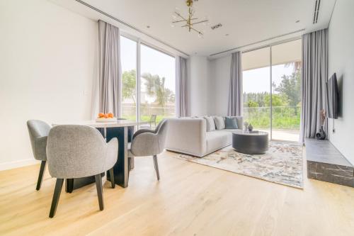 a living room with a table and chairs and a couch at Stella Stays Al-Barari in Dubai