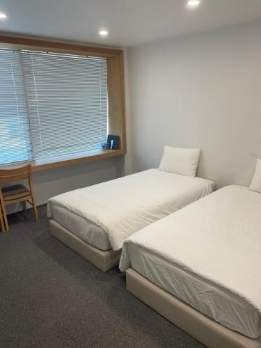 a room with two beds and a desk and a window at Urban Bridge Stay U in Busan
