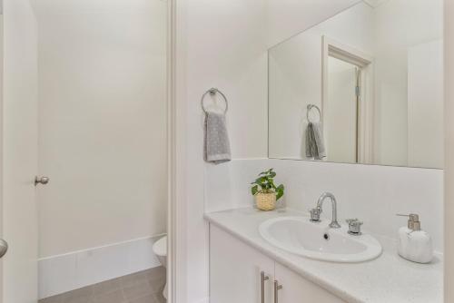 a white bathroom with a sink and a mirror at Seabreeze - 8A Charles - Luxury - Wi-Fi -Family in Port Elliot