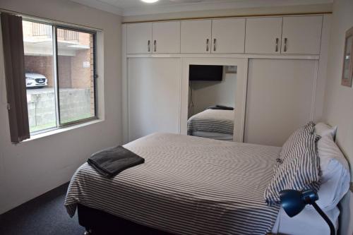 Un dormitorio pequeño con una cama y un espejo. en Pacific Court 2, en South West Rocks