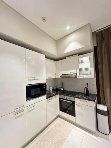 a kitchen with white cabinets and black counter tops at 2 Hawana VIP Studio in Ma‘mūrah