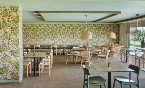 um restaurante com mesas e cadeiras e papel de parede floral em Hotel Terraverda at Empordà Golf Resort em Torroella de Montgrí