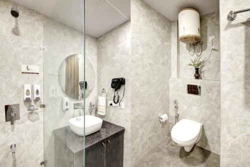 a bathroom with a toilet and a sink and a shower at Limewood stay Service Apartments Golf Course Road in Gurgaon