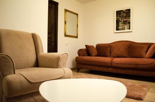 a living room with two chairs and a couch and a table at Pensiunea Almas in Piatra Neamţ