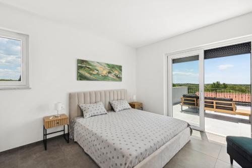 a white bedroom with a bed and a balcony at Beautiful Villa Brtonigla with pool in Brtonigla in Brtonigla