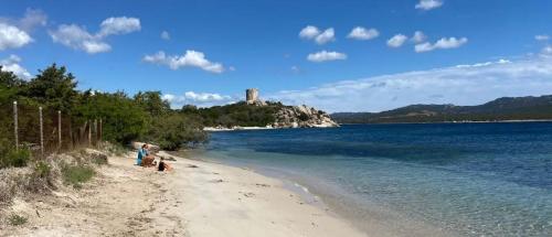 un groupe de personnes sur une plage avec un château en arrière-plan dans l'établissement Villa pieds dans l'eau sur la plage, à Pianottoli-Caldarello