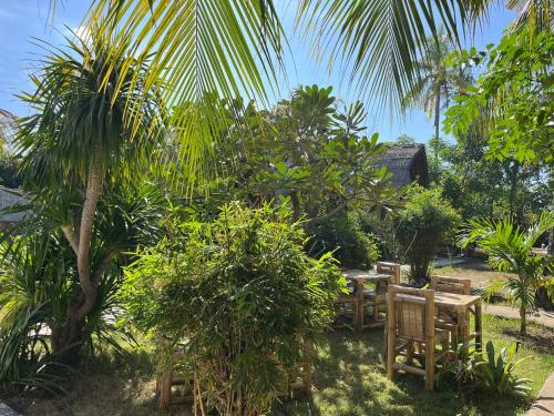 a garden with tables and chairs and palm trees at MoonBag Bungalows in Gili Air
