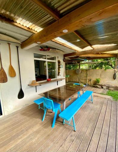 a wooden deck with a wooden table and blue benches at Les poissons du lagon YH in Uturoa