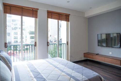 a bedroom with a bed and a tv and windows at Viet Vuong Building Ha Noi Capital in Hanoi
