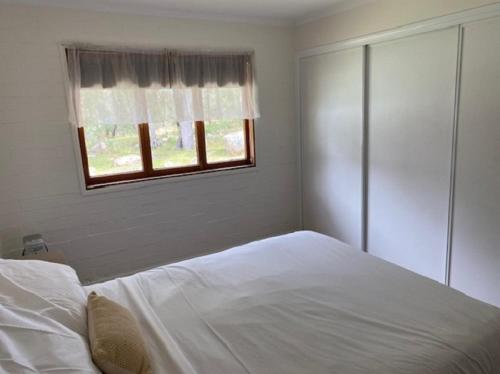 a bedroom with a white bed and a window at Girraween Country Inn in Ballandean