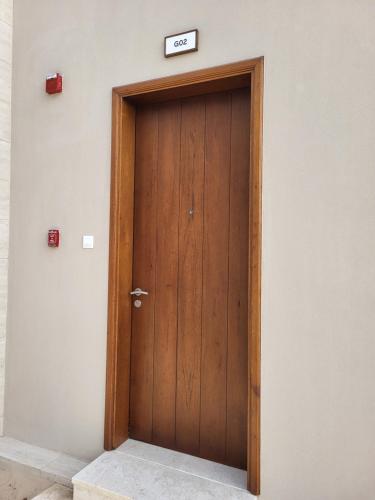 a wooden door with a sign on top of it at Gatsby's Apartment Hawana Salalah RV 14-G02 in Salalah