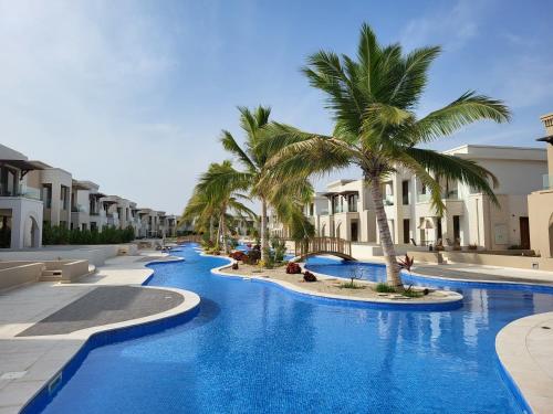 a resort swimming pool with palm trees and buildings at Gatsby's Apartment Hawana Salalah RV 14-G02 in Salalah