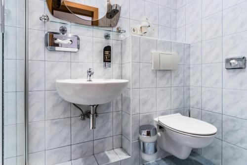 a white bathroom with a toilet and a sink at Hotel Corvinus Vienna in Vienna