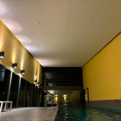 a swimming pool in a building with a yellow wall at Cozy 1 Bedroom Apt Parkside Pool Gym Parking close CBD in Melbourne