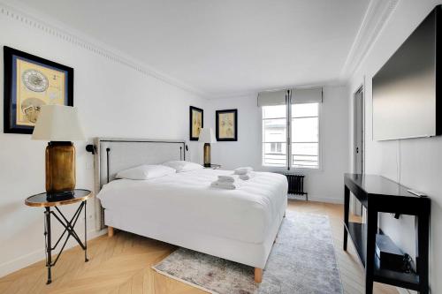 une chambre blanche avec un grand lit et une table dans l'établissement Luxury apartment - 3BR-6P - Faubourg Saint-Honoré, à Paris