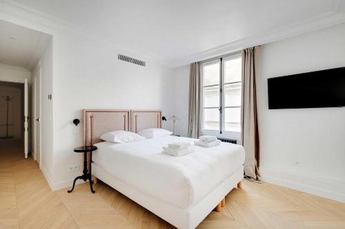 une chambre blanche avec un grand lit et une télévision dans l'établissement Luxury apartment - 3BR-6P - Faubourg Saint-Honoré, à Paris