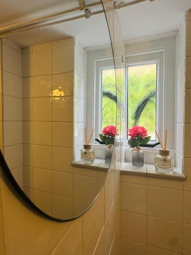 a mirror in a bathroom with flowers on a window at Souterrain Boslaan Katwijk aan zee in Katwijk aan Zee