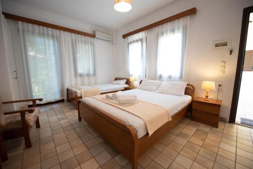 a bedroom with two beds and a table and windows at Raptis Aparthotel Sivota in Sivota