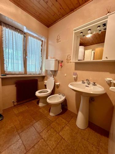 a bathroom with two toilets and a sink and a mirror at Casa Defrancesco in Panchià
