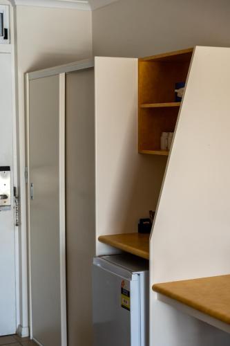 a small kitchen with a refrigerator and cabinets at Beachfront Bicheno in Bicheno