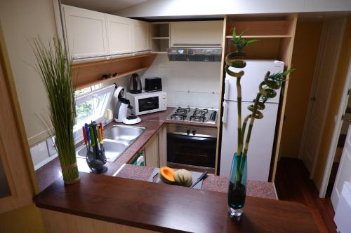 a small kitchen with a counter top with a refrigerator at LE CARRELET Mobil home climatisé INSOLITE & COSY 4 à 6 Personnes in Sémussac