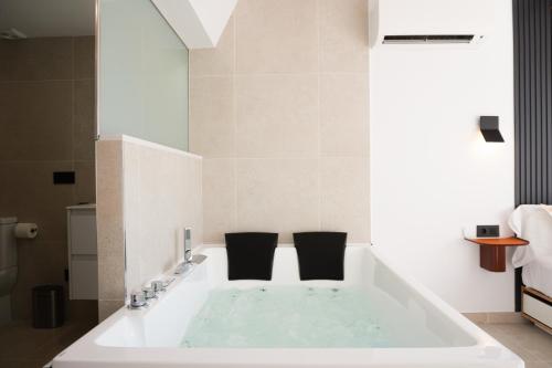 a bath tub with two black chairs in a bathroom at Ephemeral 51 Hidromasaje in Empuriabrava