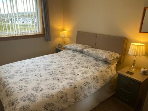 a bedroom with a bed and two lamps and a window at Riverside in Tarbert