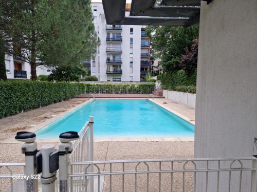 une grande piscine bleue avec un bâtiment en arrière-plan dans l'établissement Jardin D'Alexis, à Villefranche-sur-Saône
