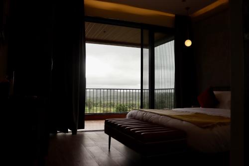 a bedroom with a bed and a large window at Dolce Villa IGATPURI in Igatpuri