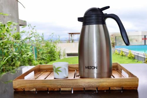 a tea kettle and a cup on a wooden tray at Dolce Villa IGATPURI in Igatpuri