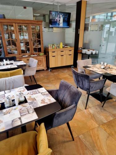 a dining room with tables and chairs and a tv at Info Hotel in Palanga