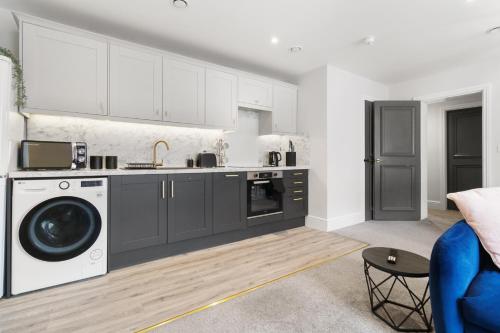 a kitchen with white cabinets and a washer and dryer at WhiskAwayStays - Victoria House - Apartment 2 in Worcester