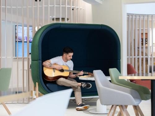 a man sitting in a suitcase playing a guitar at Novotel Suites Montpellier Antigone in Montpellier