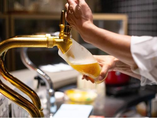 a person pouring a bottle of beer from a faucet at Tsuetate Onsen Hotel Hizenya in Oguni
