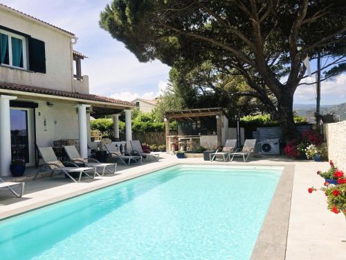 une piscine avec des chaises et une maison dans l'établissement Appart Bleu Azur, à Saint-Florent