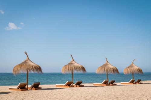a row of straw umbrellas and chairs on the beach at Estival Centurión Playa in Cambrils
