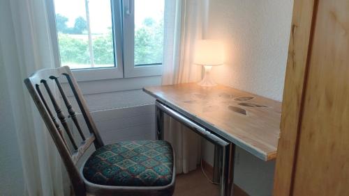 a desk with a lamp and a chair next to a window at Nisihof, Buurenzimmer Family or Single in Oberkirch