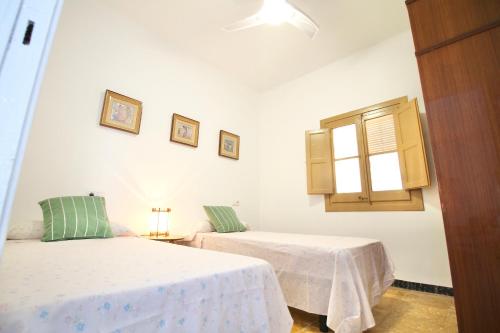 Una habitación blanca con dos camas y una ventana. en Lo Xalet de les Cases, en Les Cases d'Alcanar