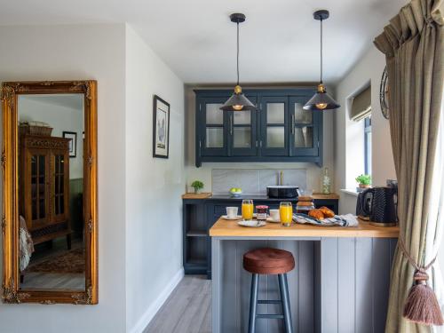 a kitchen with blue cabinets and a counter with a mirror at Sweetslade Cottage in Bourton on the Water