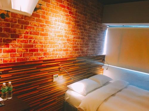 a bedroom with a brick wall and a bed at R10 Eco Hotel in Kaohsiung
