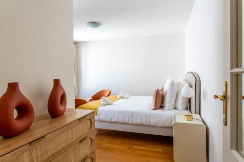 - une chambre avec un lit blanc et une commode en bois dans l'établissement Marcel s Madeleine, à Paris