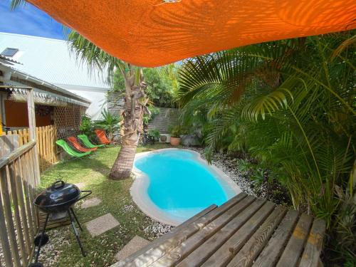 a small swimming pool in a yard with a bench at Le nid d'amour avec sa piscine et jacuzzi chauffés in Saint-Joseph