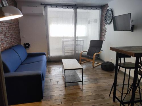 un salon avec un canapé bleu et une table dans l'établissement Appartement climatisé Le cap d'Agde, au Cap d'Agde