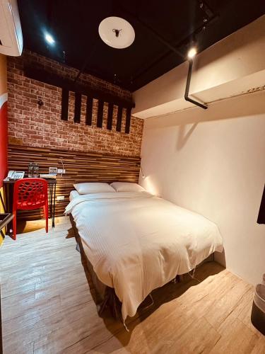 a bedroom with a bed and a table with a red chair at R10 Eco Hotel in Kaohsiung