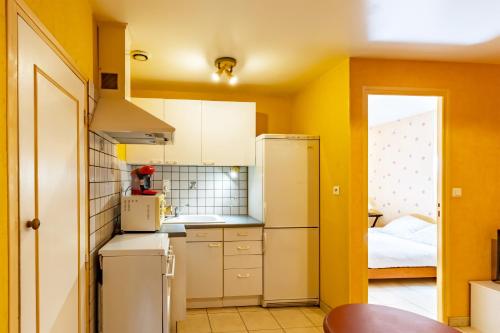 - une cuisine avec des murs jaunes et un réfrigérateur blanc dans l'établissement La Forge d'Eyliac, à Bassillac